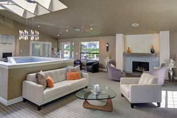 Resident Clubhouse with a fireplace and cozy couch and chair seating at 2000 Lake Washington Apartments, Renton, WA, 98056